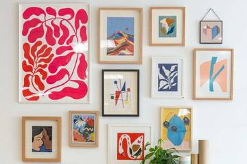 Framed needlepoint canvas stitch art displayed in a living room gallery wall setup, showing creative wall décor ideas.