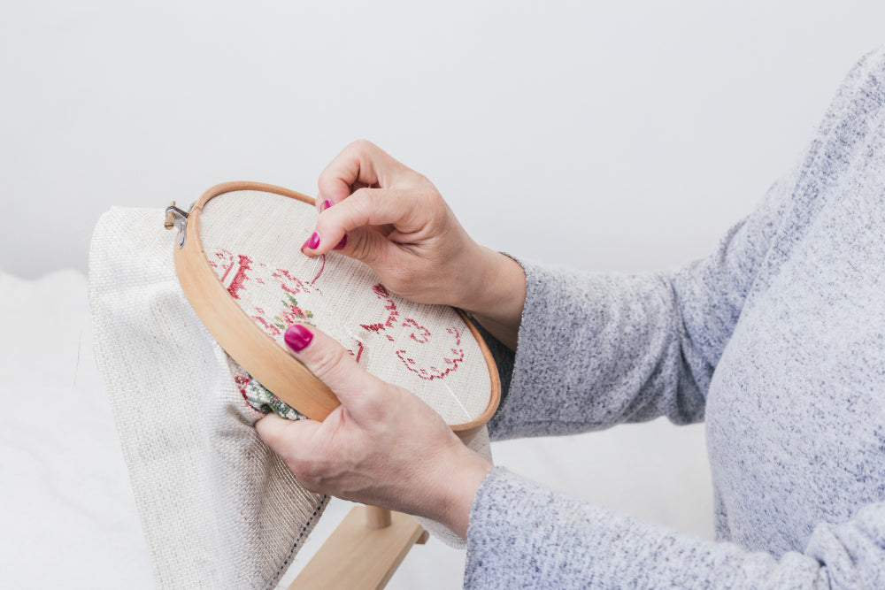 Woman stitching a calming needlepoint project on a hoop frame, practicing mindful crafting and creative stress relief through sewing.