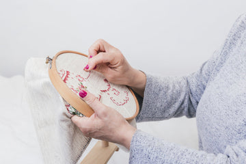 Woman stitching a calming needlepoint project on a hoop frame, practicing mindful crafting and creative stress relief through sewing.
