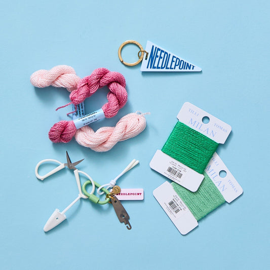 Colorful needlepoint threads, tools, and accessories on blue background showing mood-boosting craft therapy