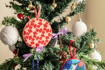 Needlepoint ornaments hanging on a Christmas tree, made using festive needlepoint kits and canvas by Atlantic Blue.