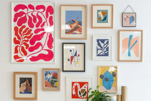 Framed needlepoint canvas stitch art displayed in a living room gallery wall setup, showing creative wall décor ideas.