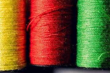 Spools of colorful threads neatly arranged for needlepoint thread organization, helping stitchers sort fibers by color, type, and project use.