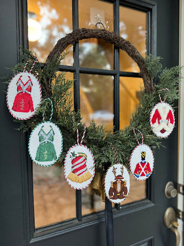 Needlepoint ornaments displayed on a holiday wreath, perfect beginner needlepoint project using festive needlepoint canvas