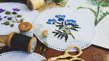 Various needlepoint designs with threads and scissors, showing beginner-friendly stitching setups and essential accessories